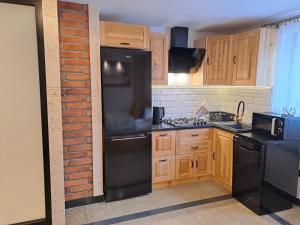 eine Küche mit schwarzen Geräten und einer Ziegelwand in der Unterkunft Apartamenty U Paliderki in Poronin