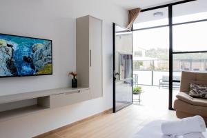 ein Wohnzimmer mit einem TV an der Wand in der Unterkunft Royal Suites Dalia - מתחם עם 4 סוויטות מהממות, בריכה מחוממת וג'קוזי in Dāliyat el Karmil