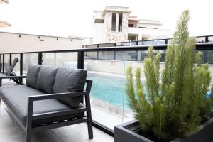 einen Balkon mit einer Bank und einem Pool in der Unterkunft Royal Suites Dalia - מתחם עם 4 סוויטות מהממות, בריכה מחוממת וג'קוזי in Dāliyat el Karmil