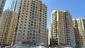 two tall buildings with cars parked in a parking lot at Tranquil Haven King Bed Ensuite Fully Furnished Bedroom in Ajman 
