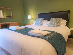 um quarto com uma cama grande e toalhas em Town End em Leighton Buzzard