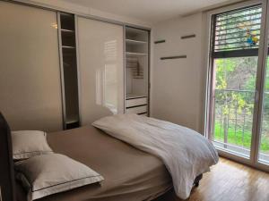 - une chambre avec un lit et une grande fenêtre dans l'établissement Oasis de Sérénité au Cœur de Lausanne : Appartement Spacieux, à Le Mont-sur-Lausanne