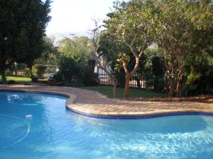 a swimming pool in a yard with trees and a fence at Lerato Bush Lodge in Pretoria
