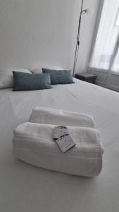 Una cama blanca con un termómetro encima. en Le petit Brigantin, en Gruissan