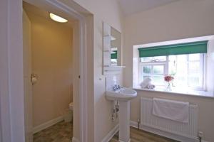 een witte badkamer met een wastafel en een raam bij The Elephant Room in Ivinghoe