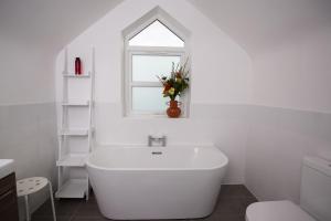 a white bathroom with a white tub and a window at Ciliau in Cardigan