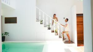 a couple walking down the stairs in a house with a swimming pool at Lugadia Villas in El Nido