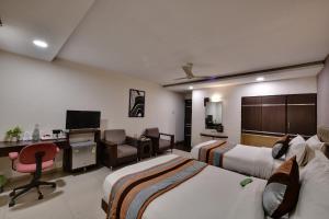 een hotelkamer met 2 bedden en een bureau bij Click Hotel Yuvraj in Surat
