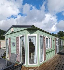 a green tiny house with a deck at The Senator 69 in Dunoon