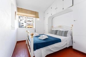 a white bedroom with a bed with a blue blanket at Acolhedor apartamento com Wifi a passos do Mar in Luz