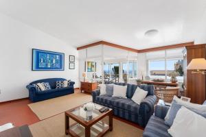 a living room with blue couches and a table at Acolhedor apartamento com Wifi a passos do Mar in Luz