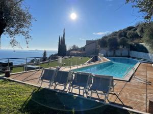 a swimming pool with two chairs on a wooden deck at Deluxe Sunrise Sky Terrasse 2 Bedroom Design Apartment & Fantastic Lake View in Maderno