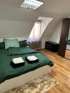 a bedroom with a green bed with two towels on it at Bivolul Negru in Blaj