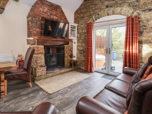 a living room with a stone fireplace and a tv at Gamekeepers Cottage in St Asaph