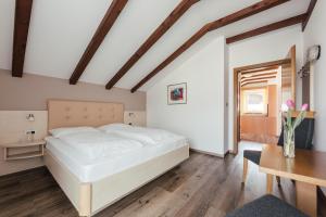 a bedroom with a white bed and a table at Hotel Garni Sirmian in Merano