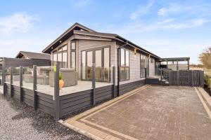 ein winziges Haus mit einer Veranda und einem Zaun in der Unterkunft Arranview Lochside Pods & Lodges all with private Hot-tubs in Fenwick
