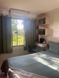 a bedroom with a bed and a desk and a window at Apartamento de campo 30min de RC in Moreno