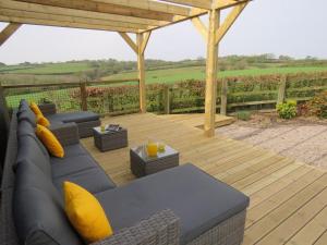 a patio with a couch and tables on a wooden deck at Sienna Cottage in Bradworthy