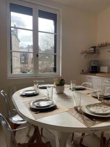 une table à manger avec des assiettes et des verres ainsi qu'une fenêtre dans l'établissement Triplex - 4 chambres - Centre historique, à Bourges