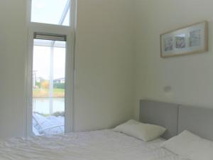 ein weißes Schlafzimmer mit einem Bett und einem Fenster in der Unterkunft Beautiful holiday home with decorative fireplace in Wemeldinge