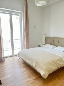 a white bedroom with a large bed and two windows at Bocconi Navigli-La casa di Zoe in Milan