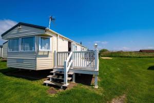 uma pequena casa azul e branca num campo em WW213 - 4B - Parkdean Resorts - Camber Sands - Com em Camber