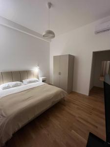 een witte slaapkamer met een groot bed en houten vloeren bij Bocconi Navigli -La casa di Zoe with free Netflix and WiFi in Milaan