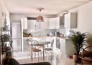 une cuisine avec des armoires blanches et une table et des chaises dans l'établissement Villa paradis, à Fréjus