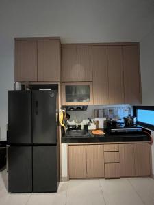 a kitchen with wooden cabinets and a black refrigerator at 2 Floor Cozy House in Wisteria Jakarta Garden City in Jakarta
