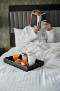 a woman laying in bed reading a book with a tray of food at Hotel Edison Times Square in New York