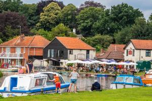 a group of people standing near boats in the water at Arthurs Cottage - rural hideaways in Norfolk in Edingthorpe