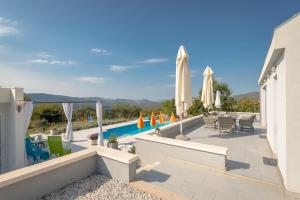 a patio with a pool and tables and umbrellas at Rustic Villa Florice with a pool in Lećevica