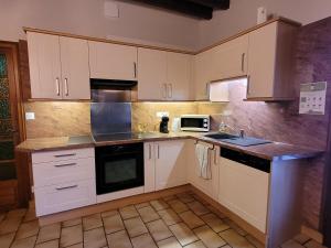 eine Küche mit weißen Schränken und einer Mikrowelle in der Unterkunft Au repos du pêcheur in Bouchamps-lès-Craon