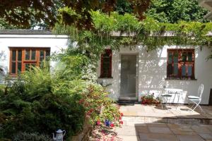 a white house with a patio and flowers at Secluded self-contained Annexe near town centre in St Austell