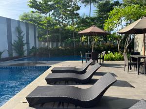 2 Floor Cozy House in Wisteria Jakarta Garden City في جاكرتا: مسبح مع كراسي وطاولات وطاولة مع مظلة