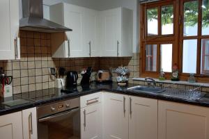 a kitchen with white cabinets and black counter tops at Secluded self-contained Annexe near town centre in St Austell