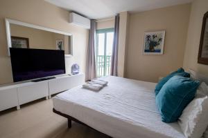 um quarto com uma televisão e uma cama com almofadas azuis em Cal Vacation em Santa Cruz de Tenerife