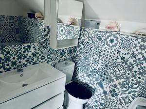 La salle de bains est revêtue de carrelage bleu et blanc. dans l'établissement Aux bonheurs des roses, à Valmont