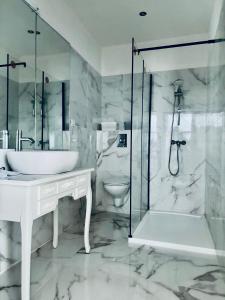 La salle de bains blanche est pourvue d'un lavabo et d'une douche. dans l'établissement Aux bonheurs des roses, à Valmont