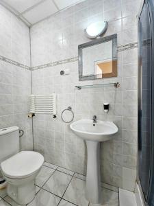 a white bathroom with a toilet and a sink at Willa Sanssouci in Kudowa-Zdrój