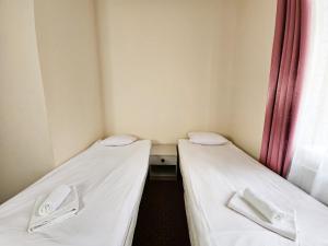 two beds in a small room with white sheets at Willa Sanssouci in Kudowa-Zdrój