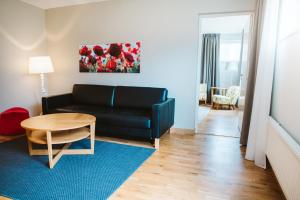 a living room with a black couch and a table at Best Western Valhall Park Hotell in Ängelholm