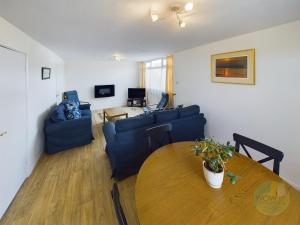 a living room with a table and a blue couch at Lovely Chalet - Welcome Holiday Park Dawlish warren in Bellaghy