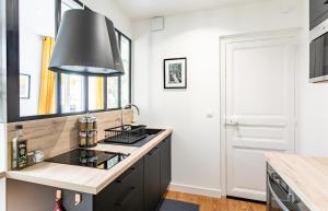 uma cozinha com uma ilha negra e uma luz de pendente preta em Lucelyne - Beau T2 rénové - Centre - Plage 400m em Dinard