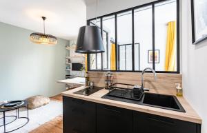 a kitchen with a sink and a large window at Lucelyne - Beau T2 rénové - Centre - Plage 400m in Dinard