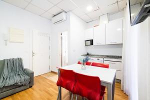 a kitchen and dining room with a white table and red chairs at Wekey Homes, Centro Granada Catedral in Granada