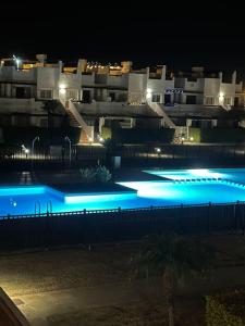 - une piscine avec des lumières bleues en face d'un bâtiment dans l'établissement Condado Naranjos 5 Casa Kyle, à Murcie