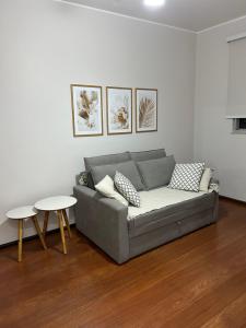 a living room with a gray couch and two tables at Apartamento Centro ao lado do Country Club in Nova Friburgo