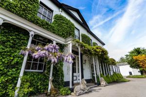 a white house covered in ivy with purple flowers at Statham Lodge Hotel in Warrington