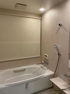 uma banheira na casa de banho com um espelho em Sunset Villa 悠生凪 ”Yunagi” em Kose